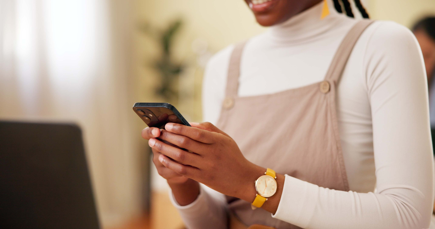 Close-up of phone in foreground with African woman's hands conducting phone interview for Hanovia Limited Tech4Dev digital skills survey in Nigeria